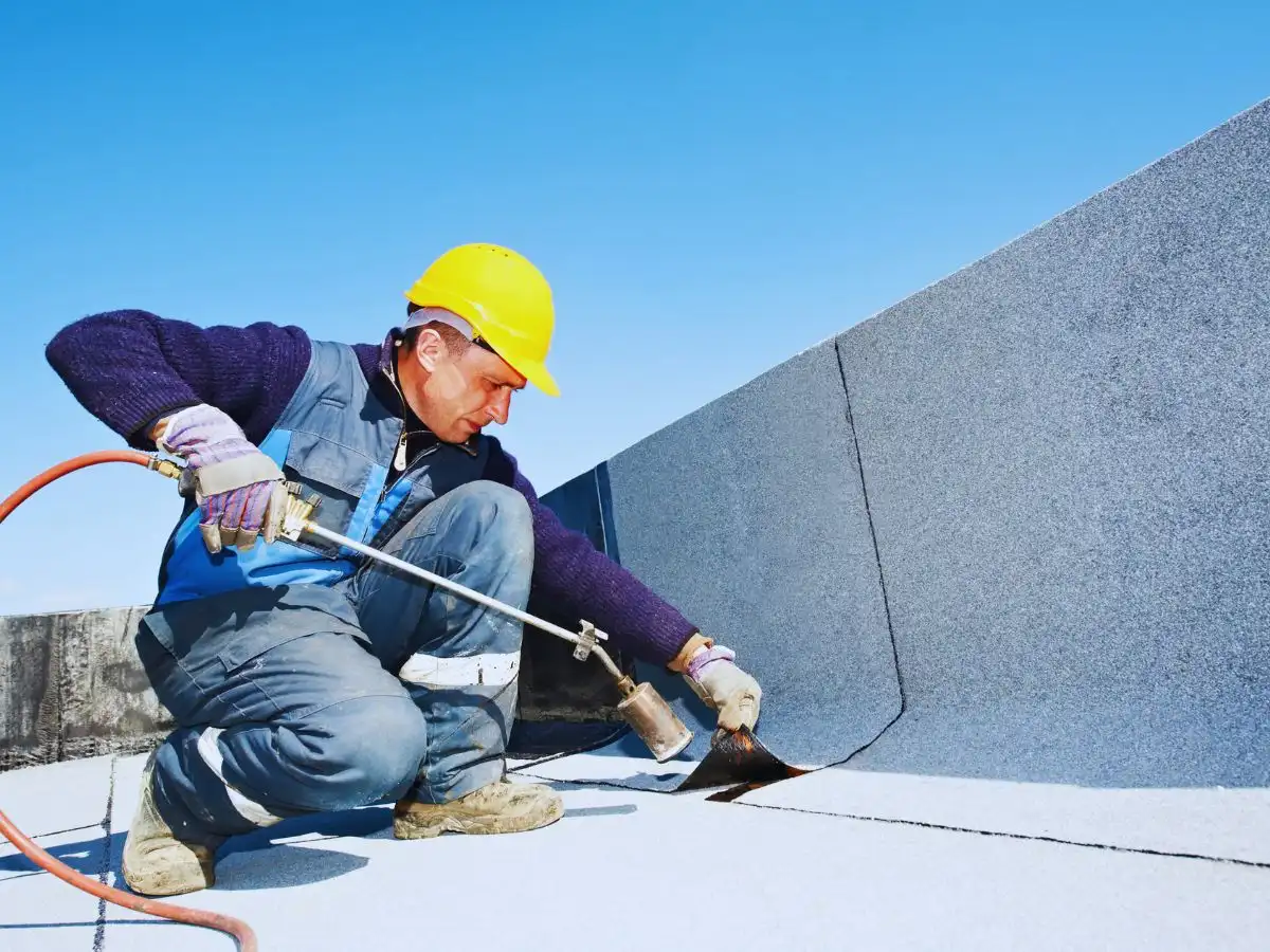 Commercial roofer heat welding a white TPO roofing membrane seam